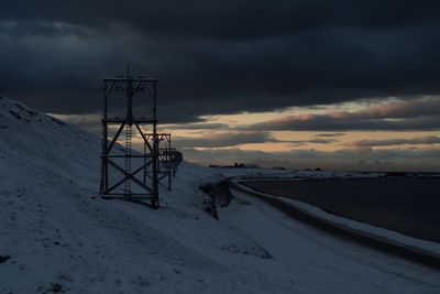 Snow covered field against sky during sunset