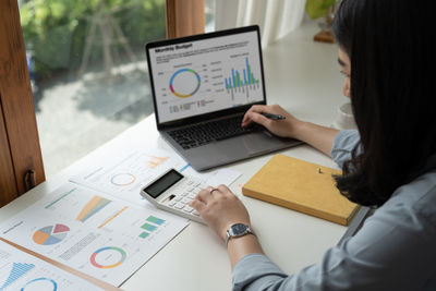 Midsection of businesswoman using laptop at office