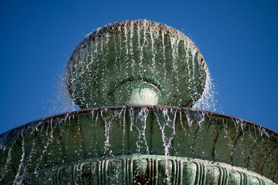 Low angle view of wet glass against blue sky