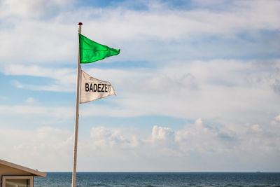 Information sign on pole by sea against sky