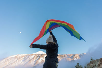 Rear view of man with umbrella against clear blue sky