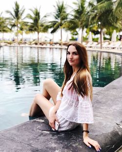 Portrait of young woman sitting on swimming pool