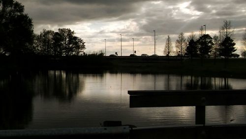 Reflection of silhouette trees in water against sky