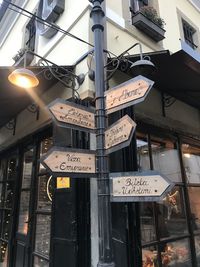 Low angle view of information sign by buildings in city