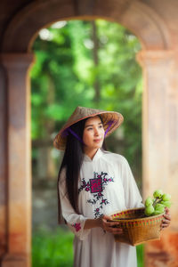 Woman in asian style conical hat standing in corridor