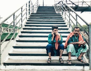 Full length of men sitting on staircase