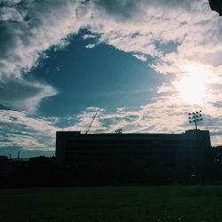 View of field against cloudy sky