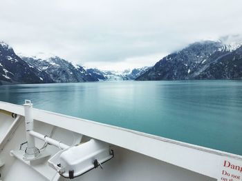 Scenic view of sea by snowcapped mountains against sky