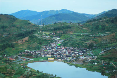 Aerial view of townscape by mountains against sky