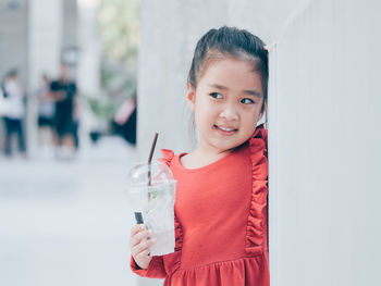 Smiling girl holding drink while looking away