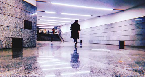 Rear view of man walking in illuminated building