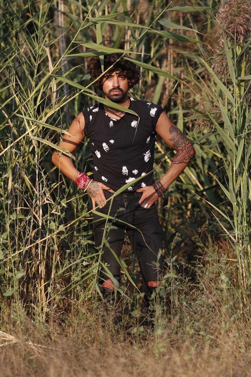 YOUNG MAN STANDING BY PLANTS