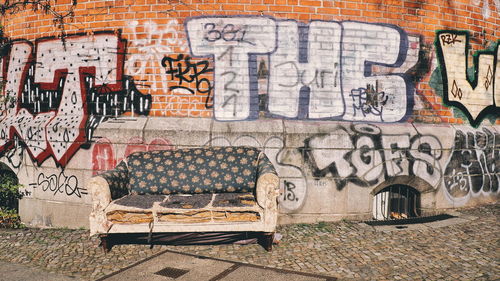 Old sofa by graffiti on wall