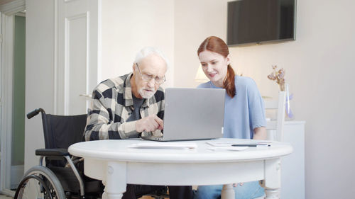 Side view of woman using laptop at home