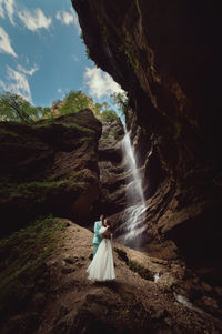A young man and his wife are standing in an embrace in a canyon against the backdrop of a high