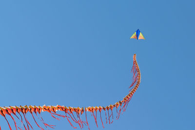 Low angle view of kite flying against clear blue sky