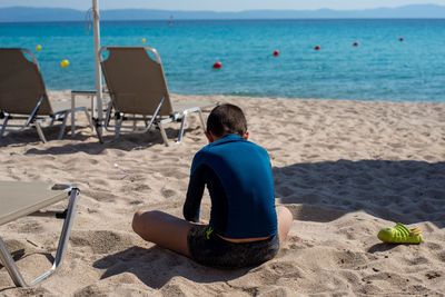 Rear view of man sitting on beach