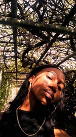 Close-up portrait of young woman standing against trees in forest