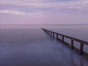 Pier over sea against sky at sunset