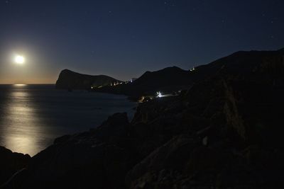Scenic view of rocky beach against sky at night