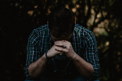 Close-up of worried young man sitting outdoors at night