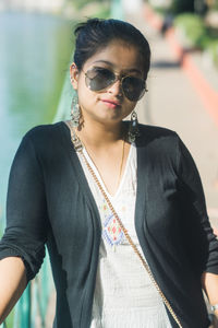 Portrait of young woman wearing sunglasses standing outdoors