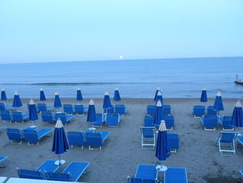 Chairs on beach against clear blue sky