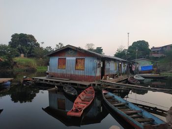 Boats moored on river by buildings against sky