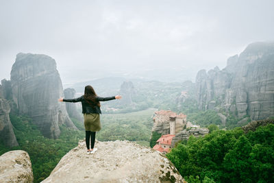 Rear view of woman standing on rocky mountain