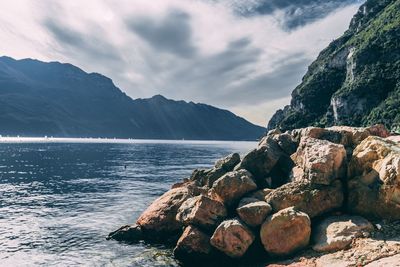 Scenic view of sea by mountains against sky