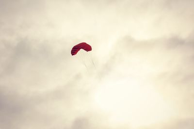 Low angle view of red paragliding against sky