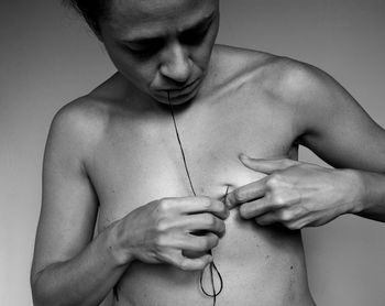 Close-up of shirtless man against gray background