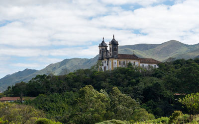 Castle by tree and buildings against sky