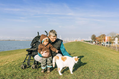 Senior man with granddaughter and cat on land during sunny day