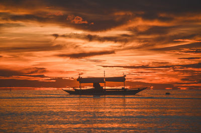 Silhouette sailboat in sea against sky during sunset