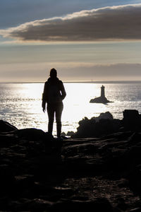 Rear view of silhouette man standing at beach during sunset
