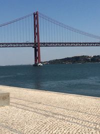Suspension bridge over sea against sky