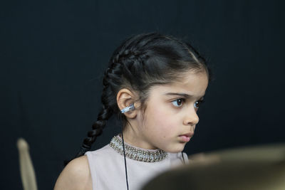 Girl wearing hearing aid while playing drum against wall