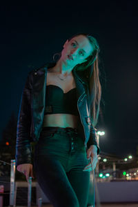 Portrait of young woman standing against sky at night