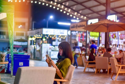 Woman using phone while sitting on table