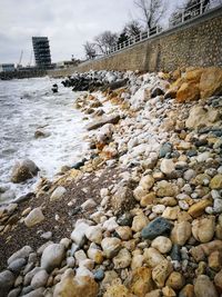 Pebbles on snow in city against sky