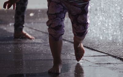 Low section of people running on wet road during rainy season