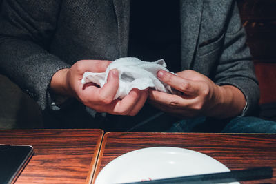 Midsection of man holding napkin while sitting at table