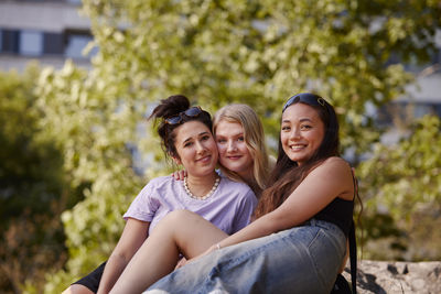Three young female friends sitting together and looking at camera