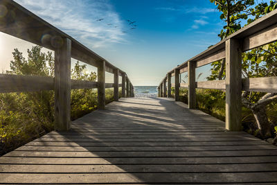 View of wooden footpath leading towards water