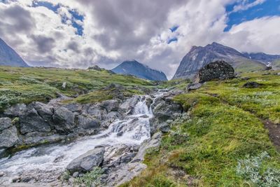 View of waterfall against cloudy sky