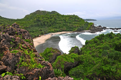 Scenic view of rocks by sea against sky