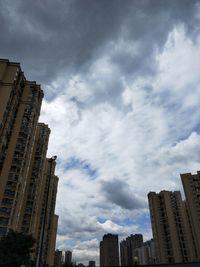 Low angle view of skyscrapers against cloudy sky