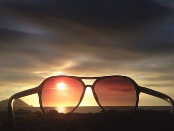 Abandoned sunglass on seashore at sunset