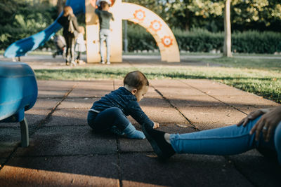 Rear view of boy playing on slide at playground